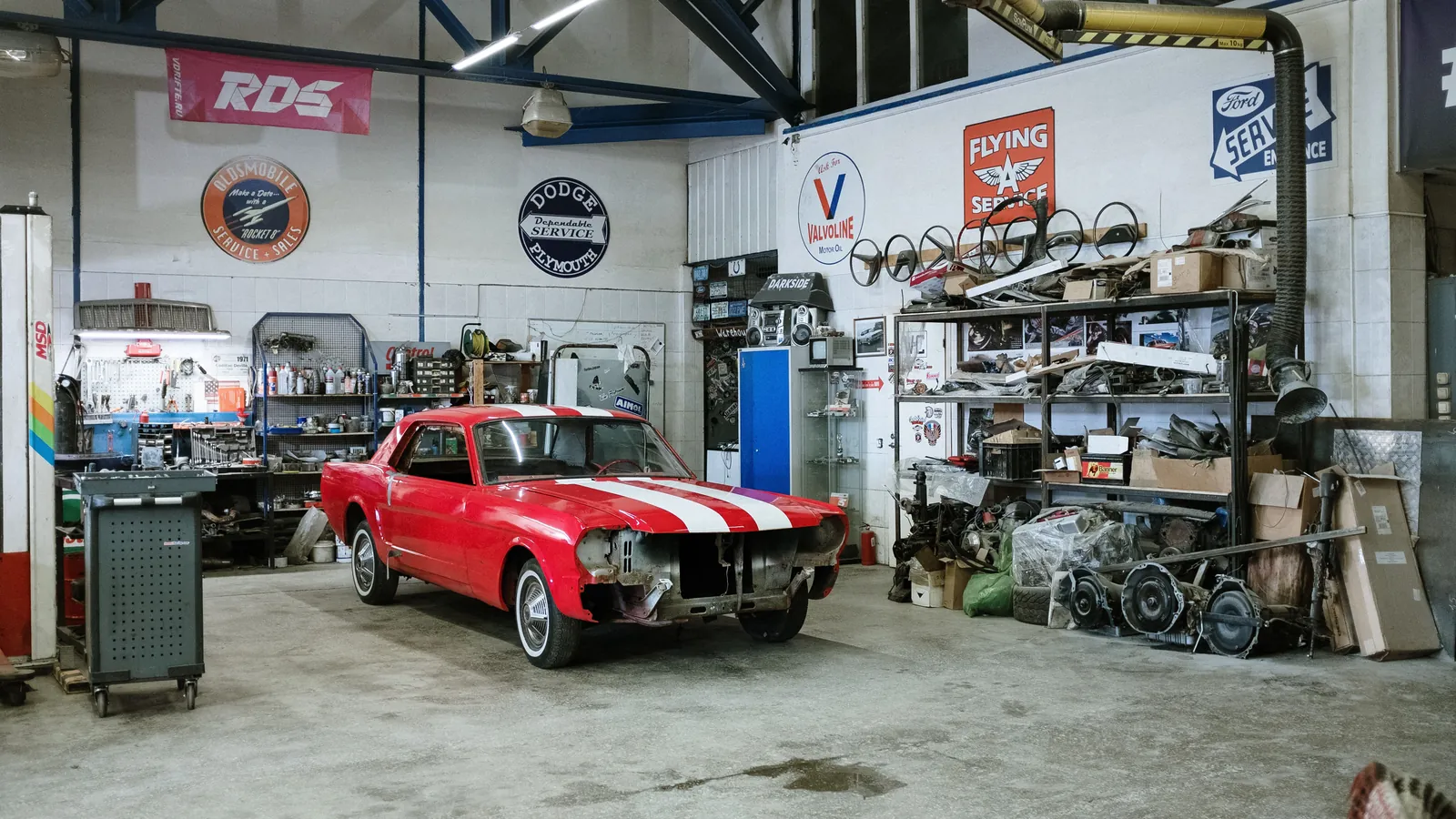 L'atelier : un véhicule en cours de réparation, l'outillage et les pièces tout autour